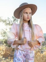 Young girl wearing a wide-brimmed hat and patterned outfit outdoors